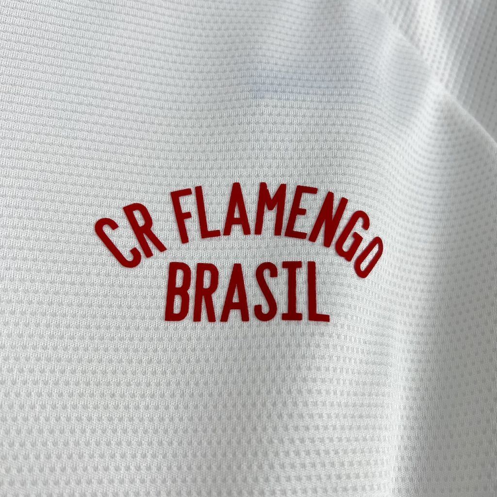 "Close do escudo CRF bordado na camisa Flamengo retrô 1981 branca e vermelha, destacando acabamento de alta qualidade."